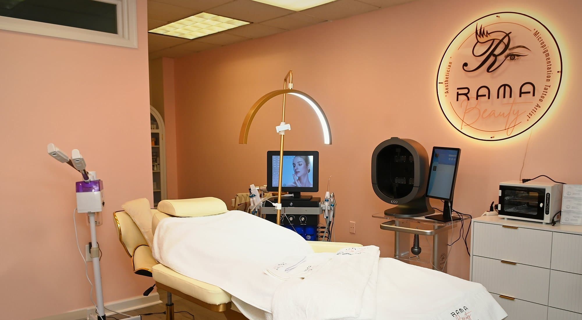 The Rama Beauty treatment room with the facial bed, hydro-facial system, skin analyzer and lit sign